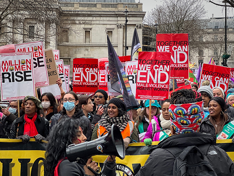 Million Women Rise march A crowd of women march in London carrying placards that read “Million Women Rise” and “We can end male violence against women.” A woman carries a bullhorn in the foreground.