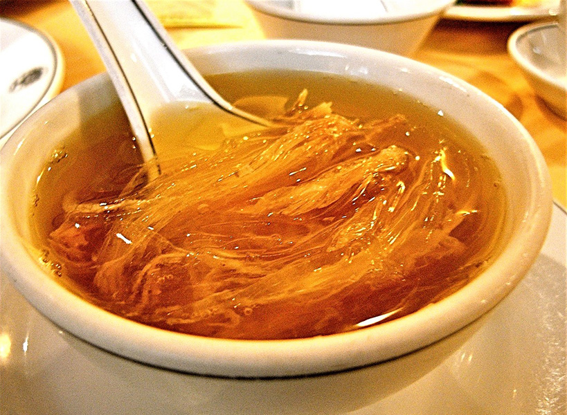 A dish of yellowish broth with shark fin that, to the eye, resembles cellophane noodles.