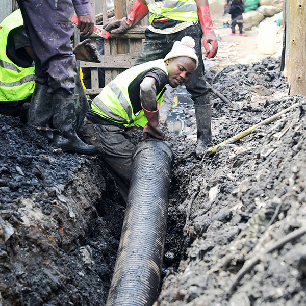 Simplified sewer A man in a trench moves a big piece of pipe