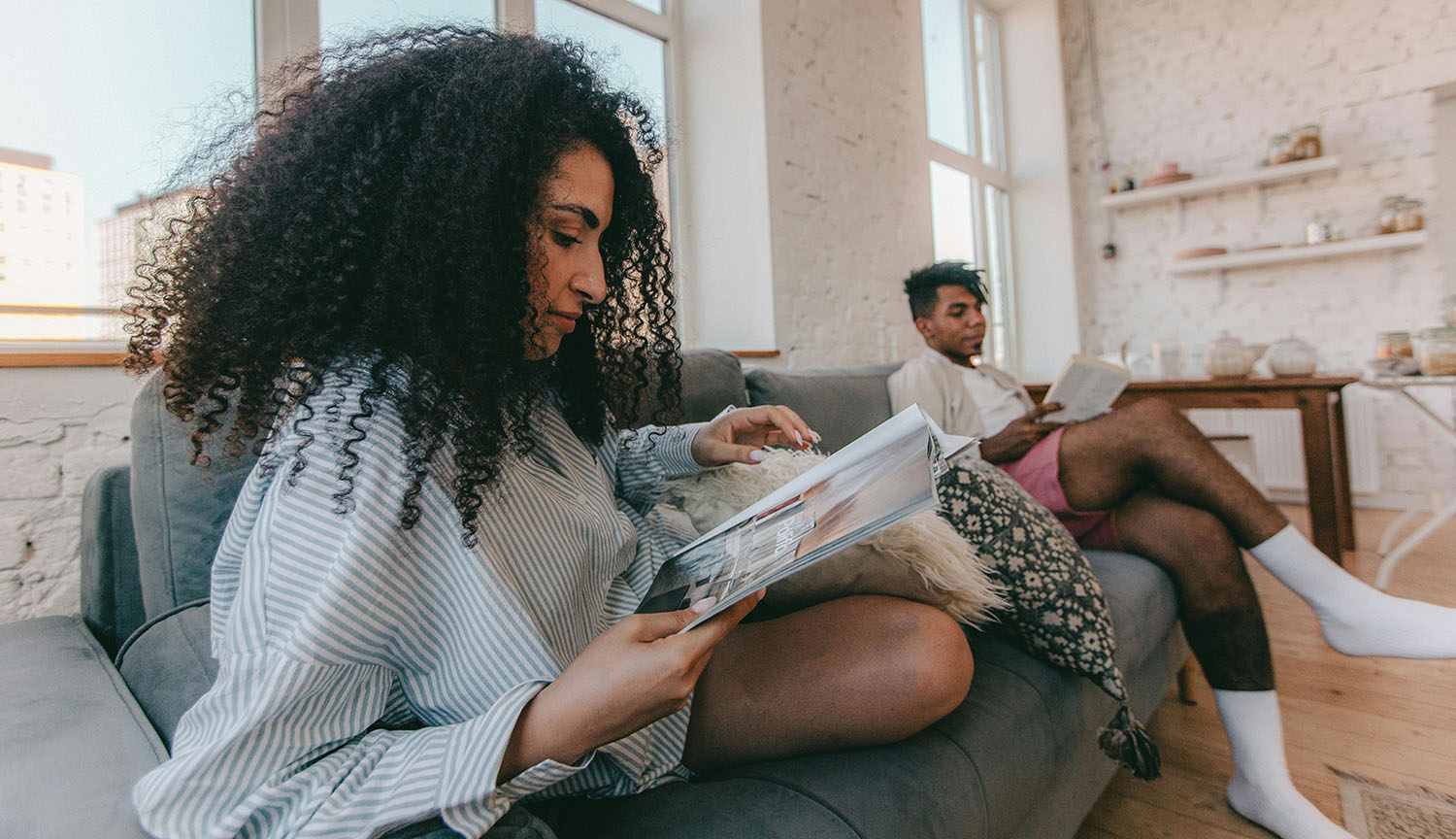 Photograph of a couple sitting on a couch. They are reading quietly.