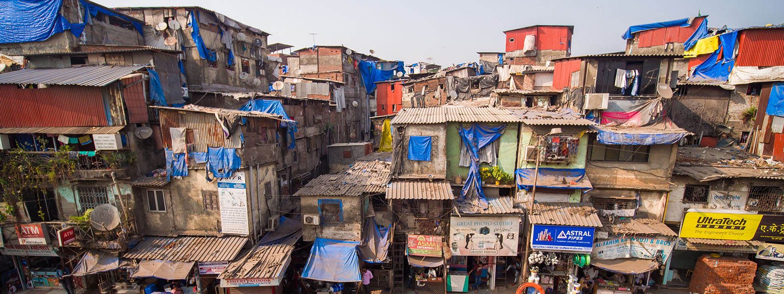 Crowded makeshift buildings of concrete and siding stacked on one another.