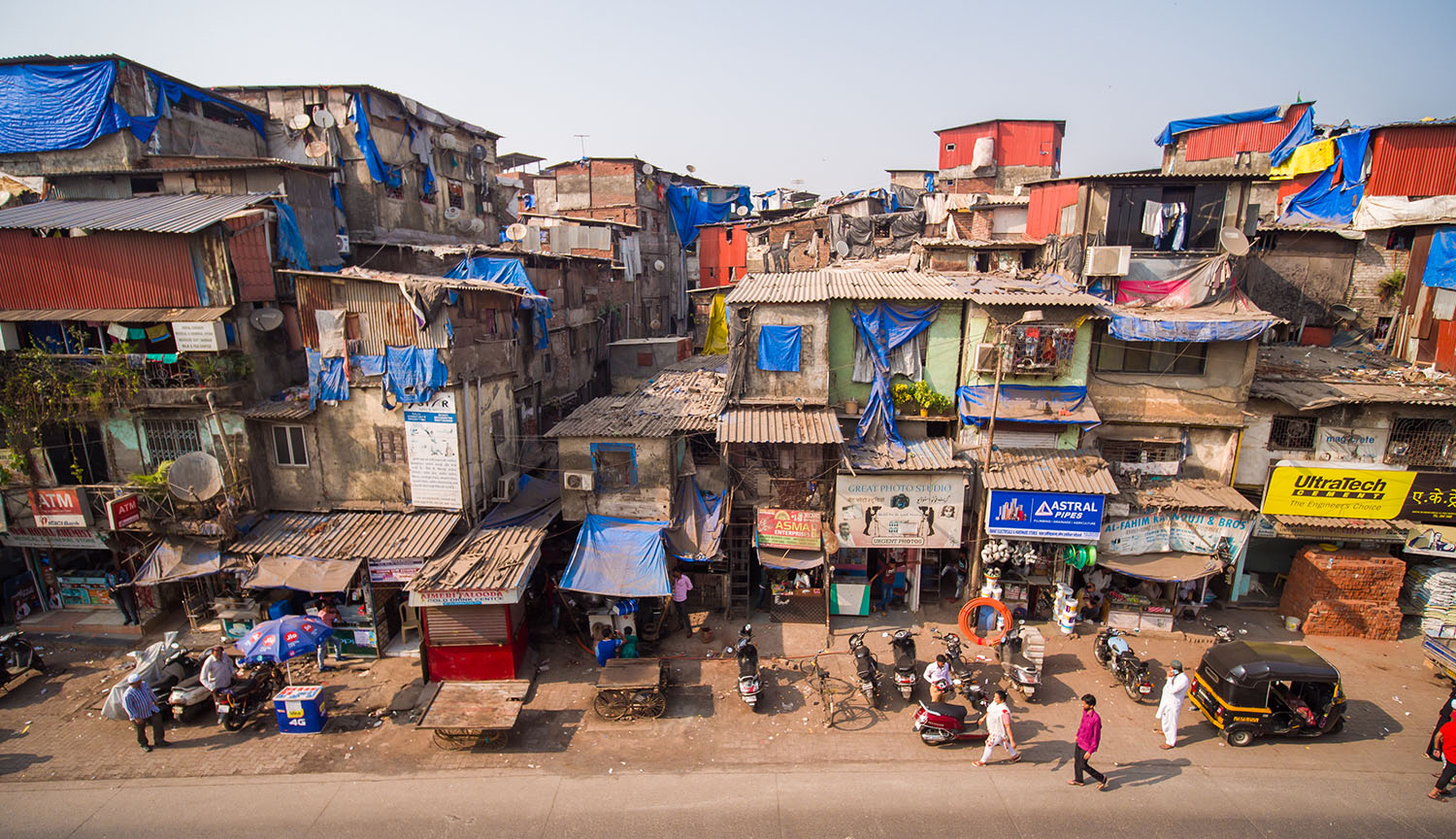 Crowded makeshift buildings of concrete and siding stacked on one another.
